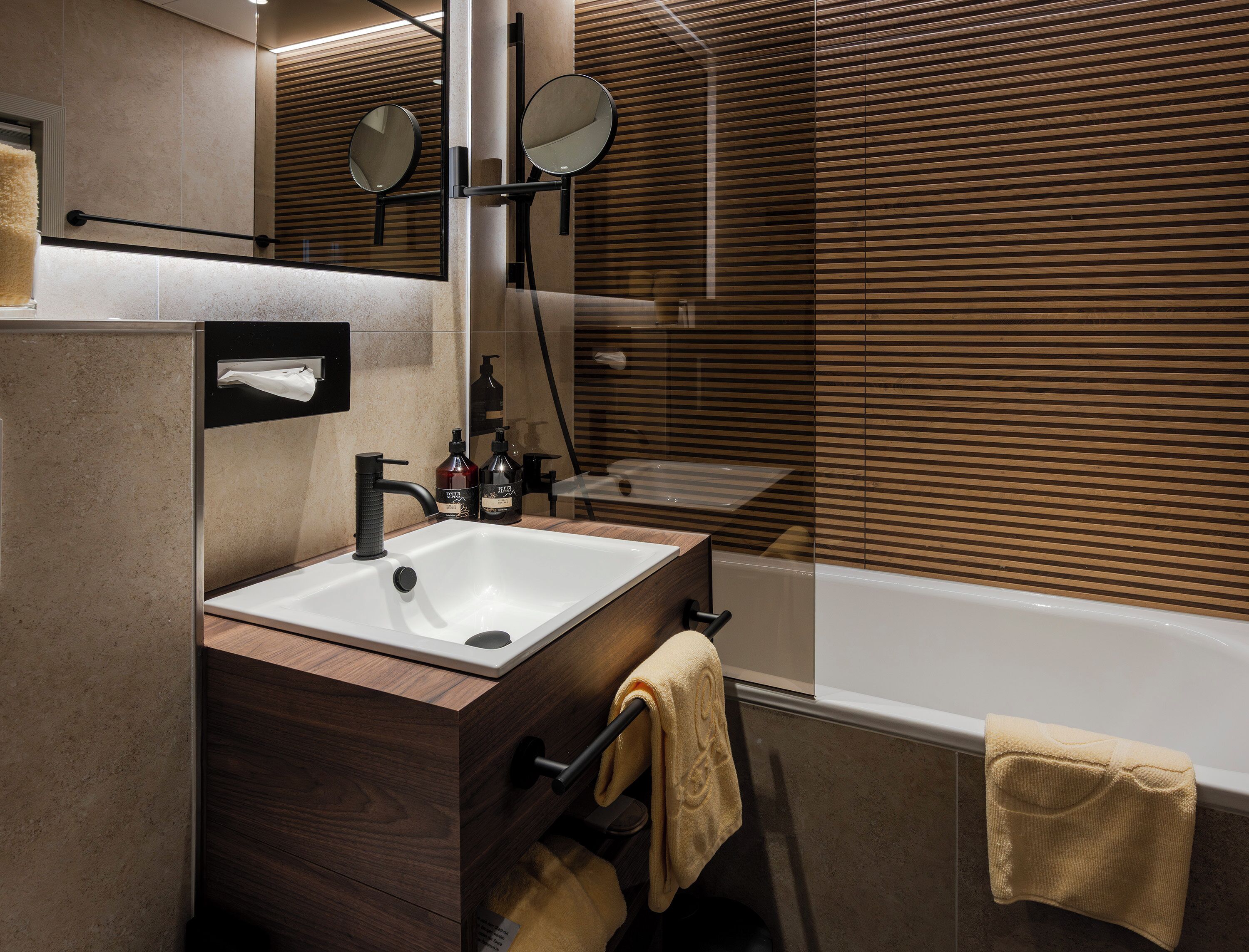 A modern bathroom with a sink, mirror, towel rack, and a bathtub.