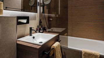 A modern bathroom with a sink, mirror, towel rack, and a bathtub.