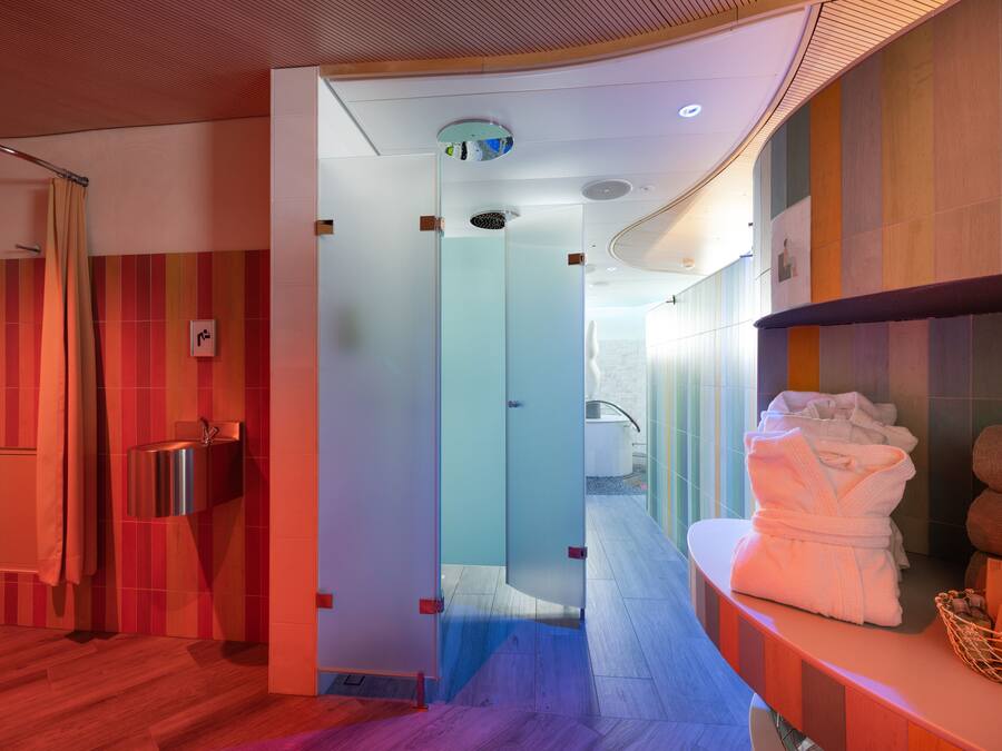 A modern bathroom with a glass shower enclosure, a sink, and a towel rack.