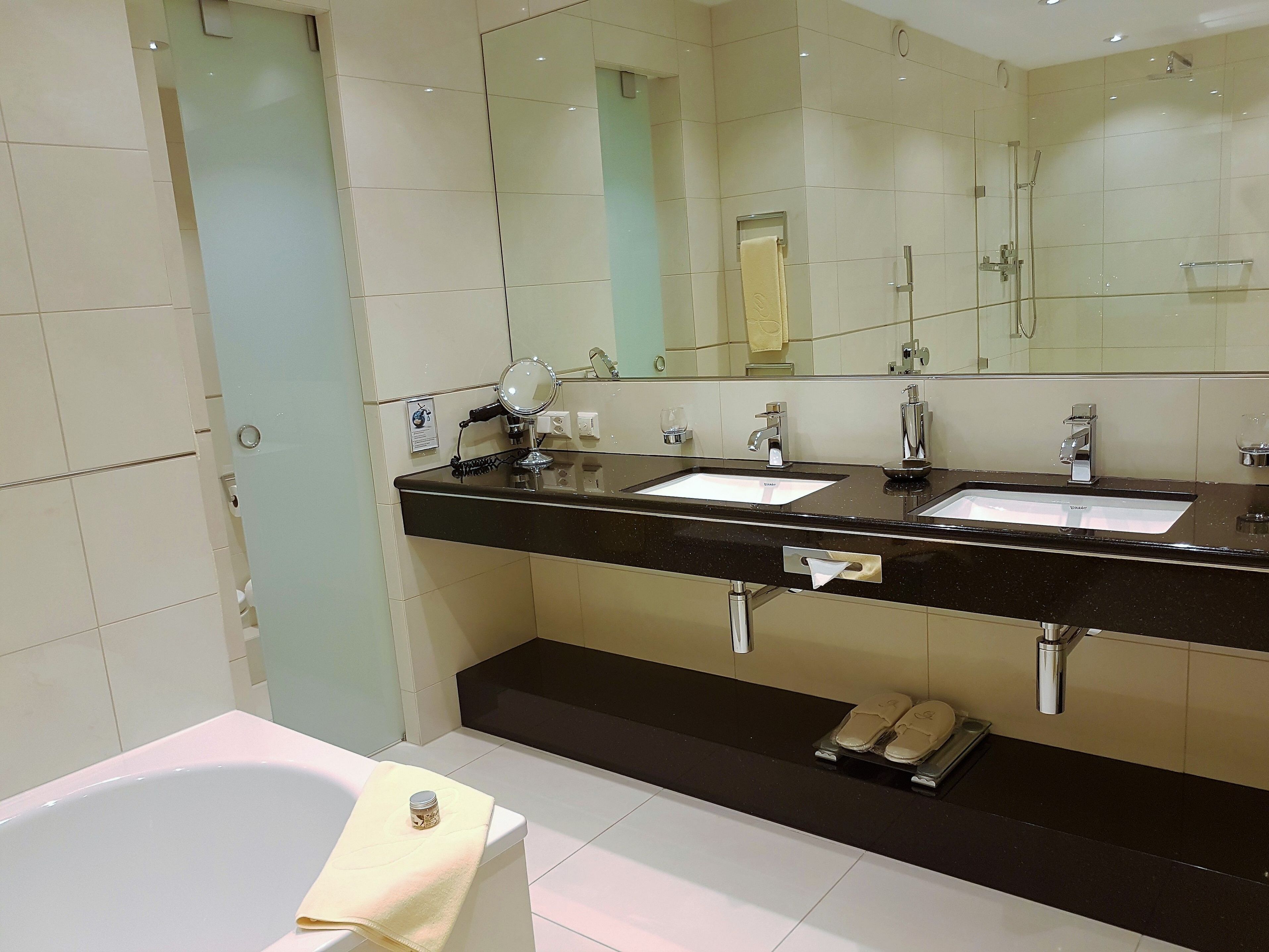 Un baño moderno con dos lavamanos, un espejo grande y una bañera.