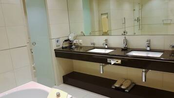 Un baño moderno con dos lavamanos, un espejo grande y una bañera.