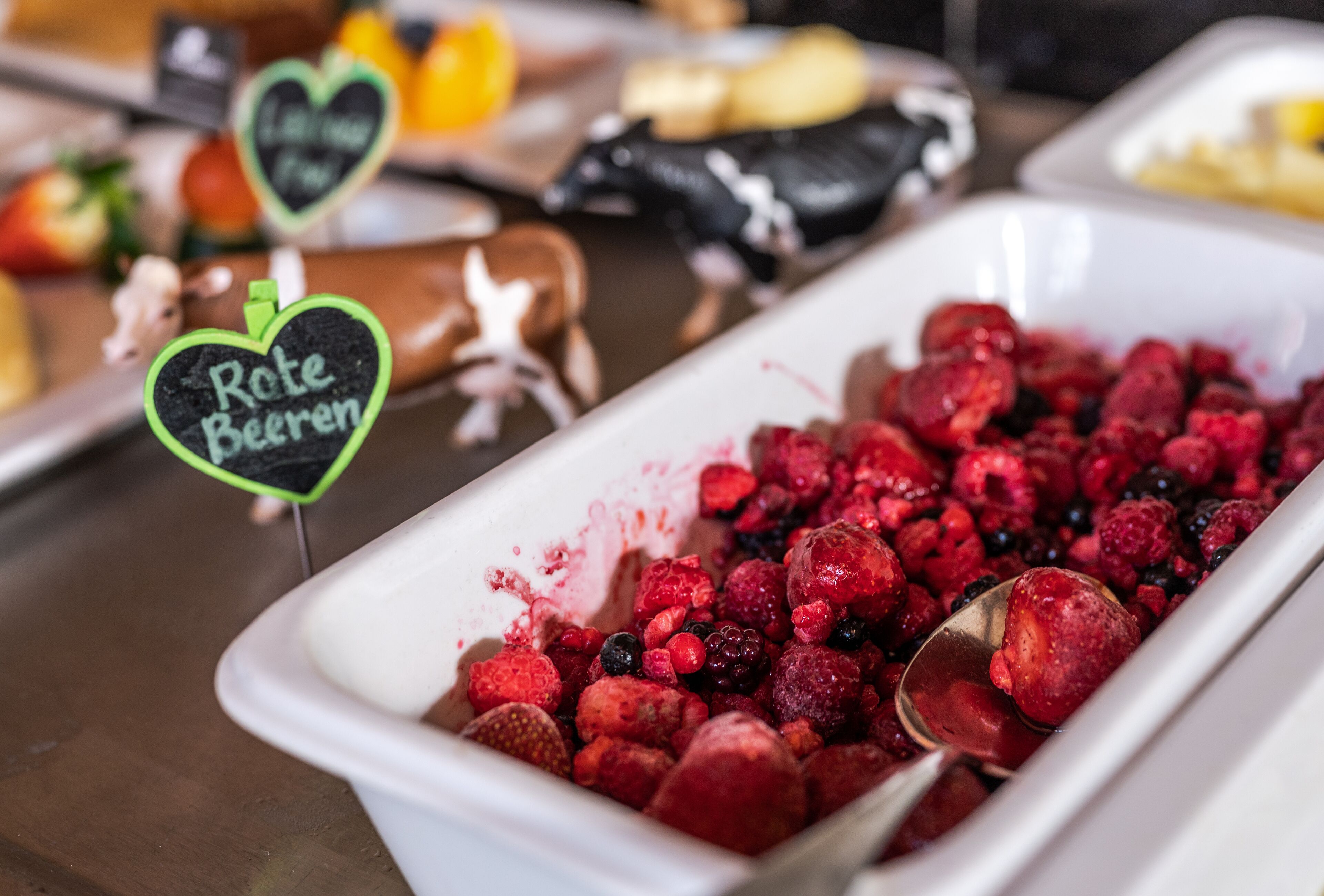 Un bufé con una variedad de frutas y un letrero que dice 'Rote Beeren'.