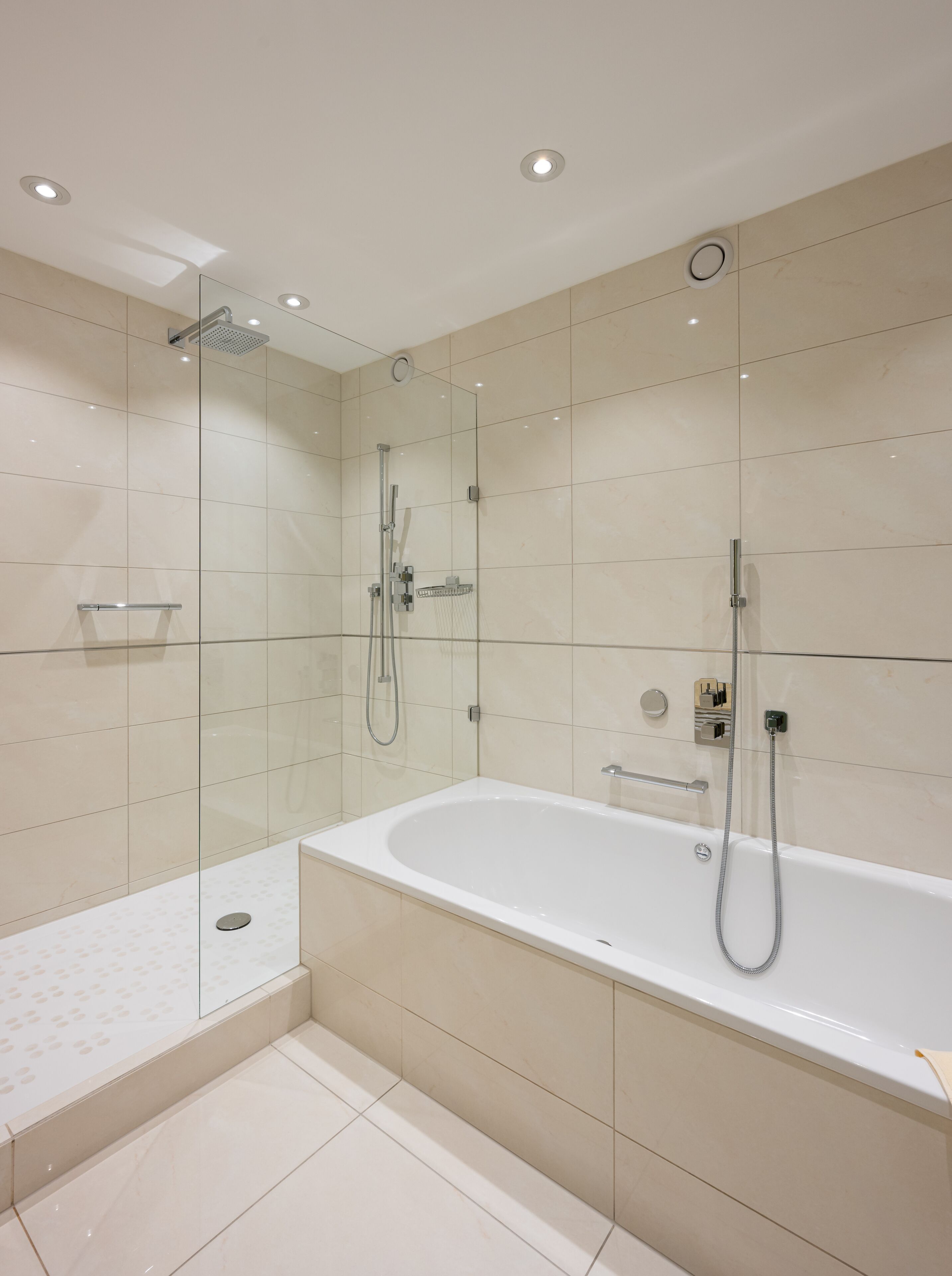 Un baño moderno con ducha envuelta en vidrio, una bañera independiente y un inodoro con cerramiento de vidrio.