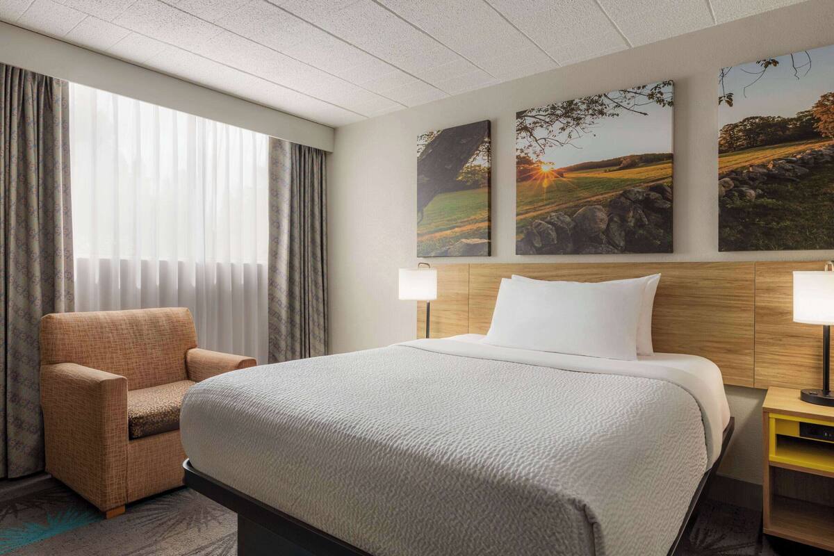 Ein Hotelzimmer mit einem großen Bett, einem Sessel und zwei Wandlampen.