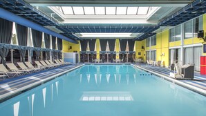 Una amplia piscina cubierta con numerosas tumbonas y una claraboya.