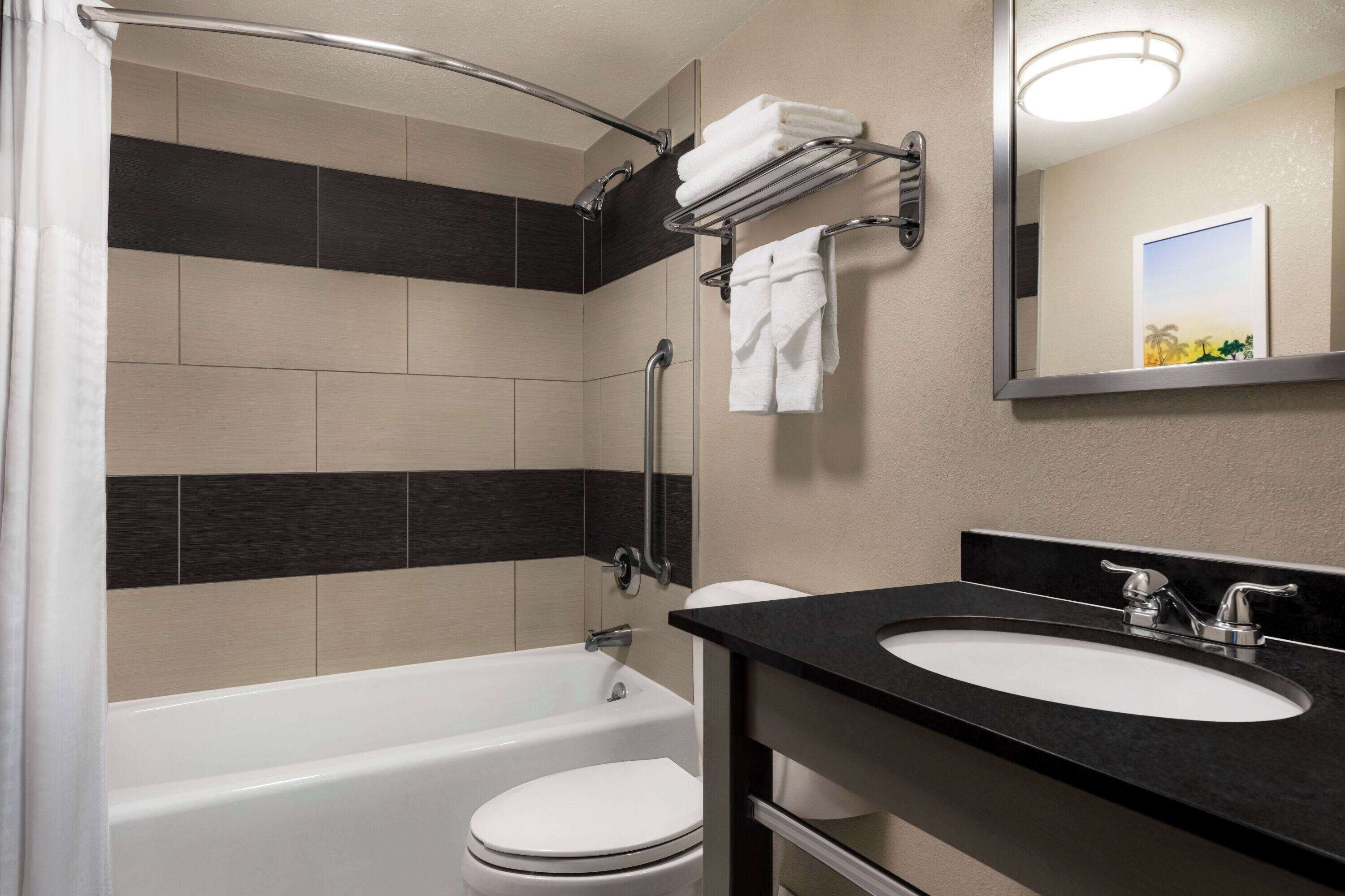 A modern bathroom with a bathtub, toilet, and a sink with a mirror.