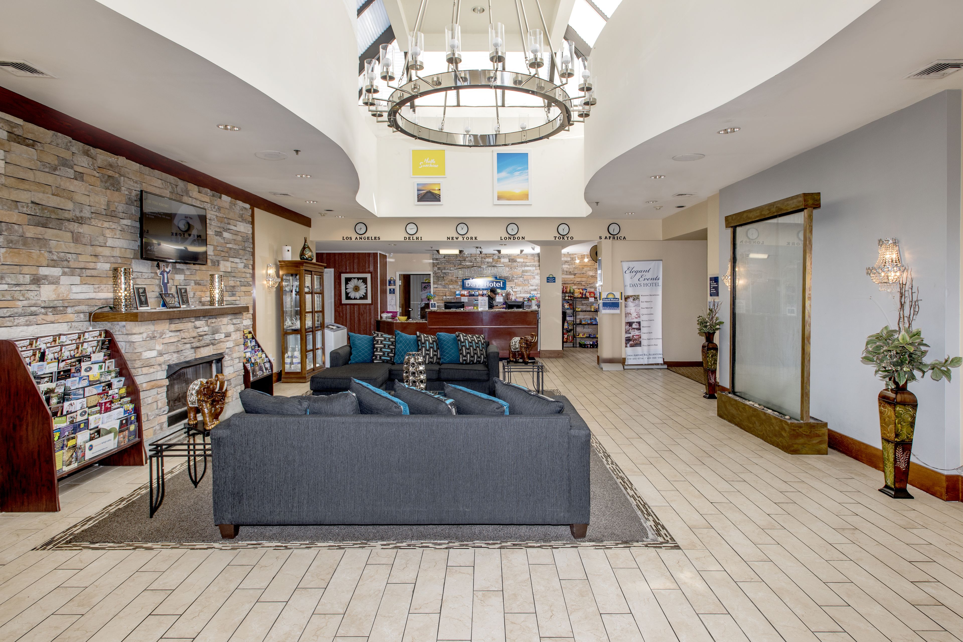 Eine großzügige Lobby mit grauem Sofa, Kamin, einer Chandelier und einem Empfangsbereich.