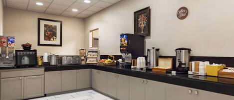 A hotel kitchen with a coffee station, a framed picture, and a coffee bar sign.