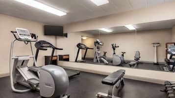 A gym with cardio equipment, weights, and a mirror.