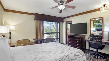 Habitación de hotel con una cama grande, un escritorio con computadora, televisión y ventilador de techo.