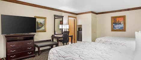 Une chambre d’hôtel avec un grand lit, un bureau avec une chaise, une commode, un téléviseur et deux tableaux accrochés aux murs.