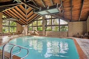 Una piscina techada, una piscina al aire libre, sombrillas