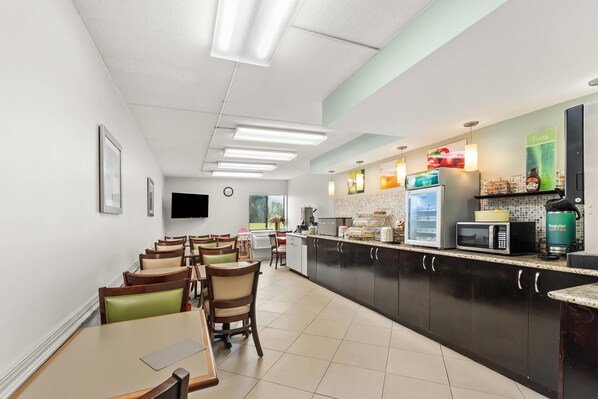 A modern kitchen with a flat-screen TV, a microwave, and a coffee machine.