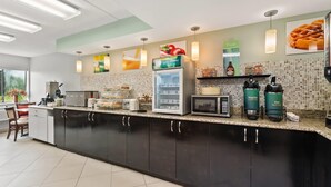 A modern kitchen with a coffee station, a refrigerator, and a microwave.