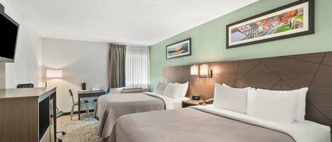 A hotel room with two beds, a desk, a chair, a TV, and a painting on the wall.