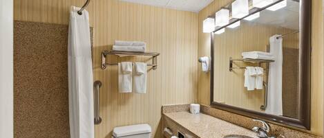 A bathroom with a shower, toilet, sink, and towel rack.