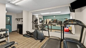 A gym with treadmills, an elliptical, dumbbells, and a bench.