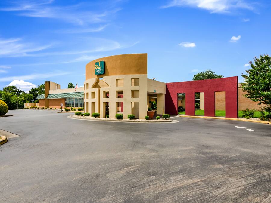 A hotel with a curved facade, a green sign, and a red building adjacent to it.