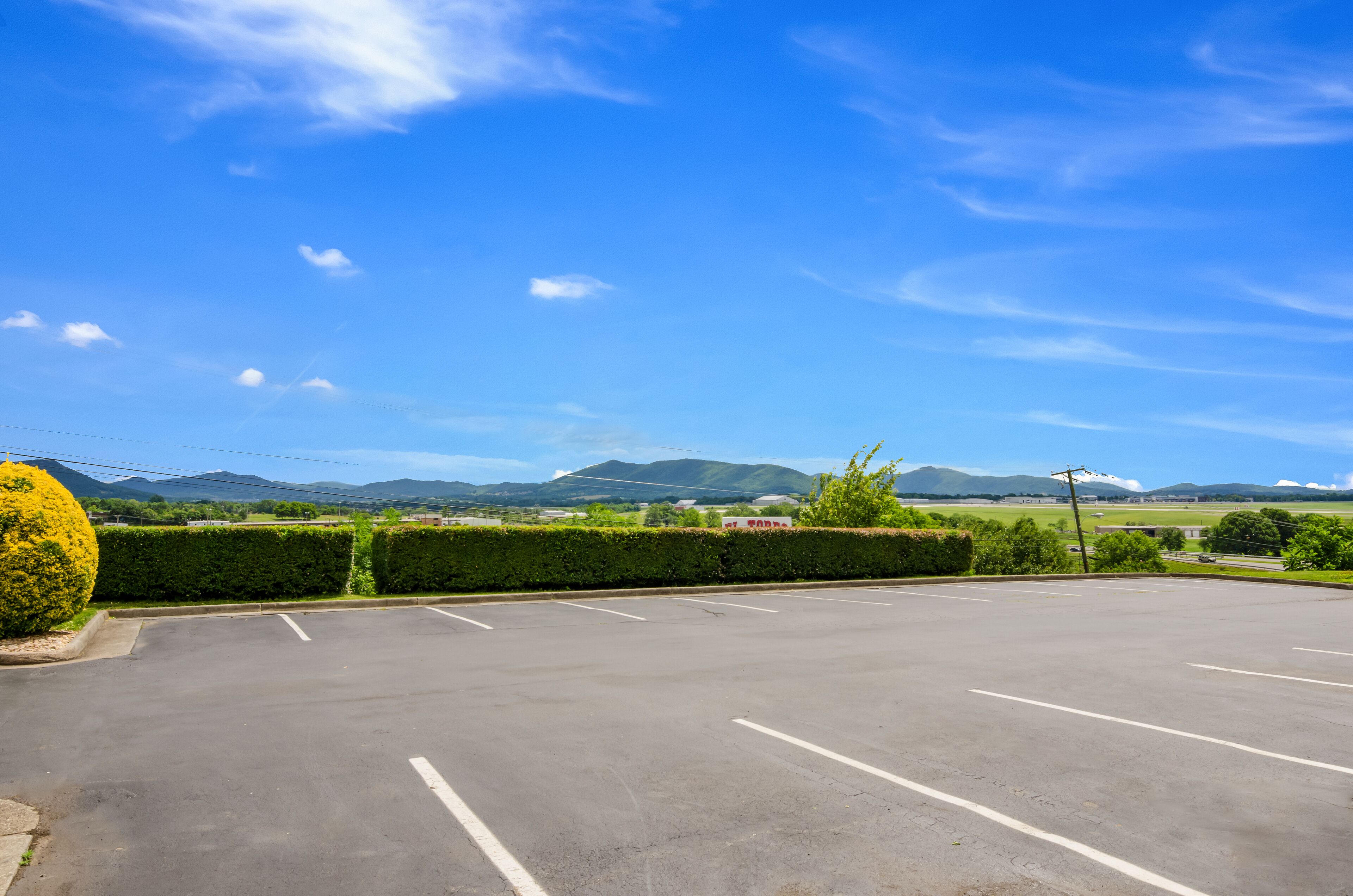 A parking lot with clear blue skies and distant mountains.
