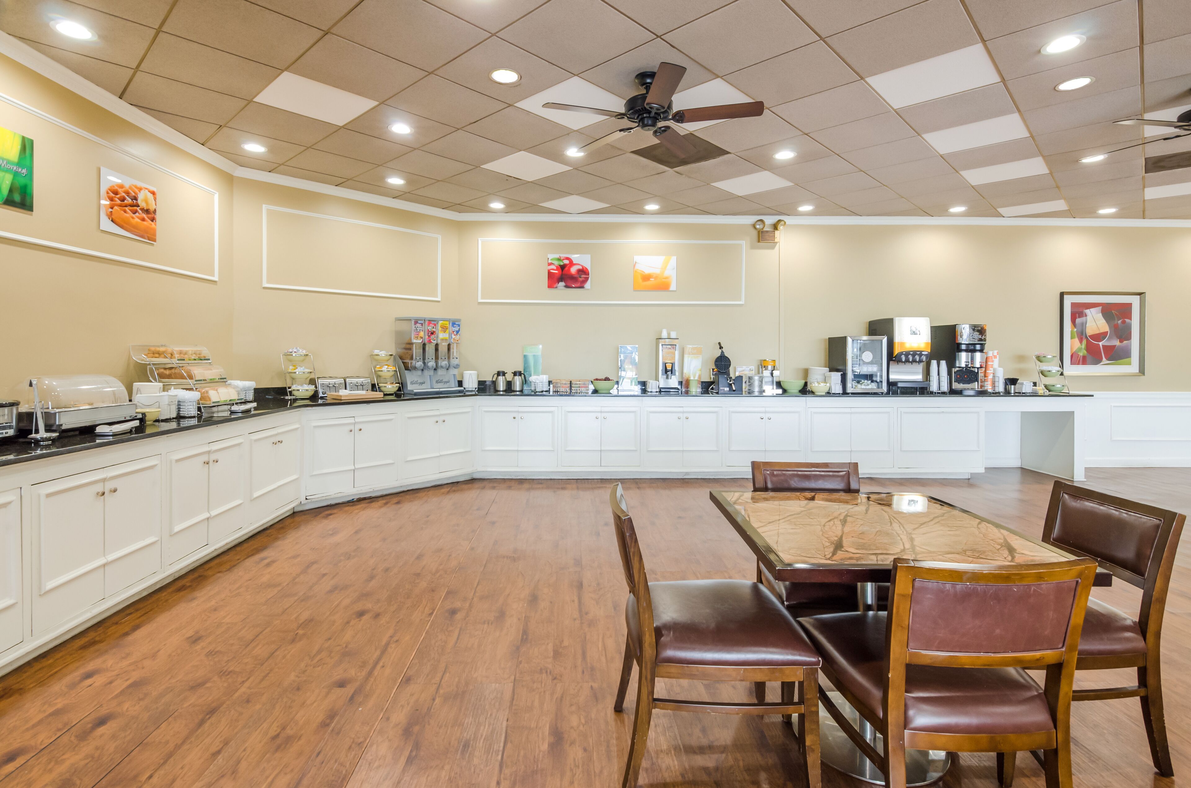 A spacious kitchen with a large island, white cabinetry, and a dining area with wooden chairs.