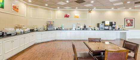 A spacious kitchen with a large island, white cabinetry, and a dining area with wooden chairs.