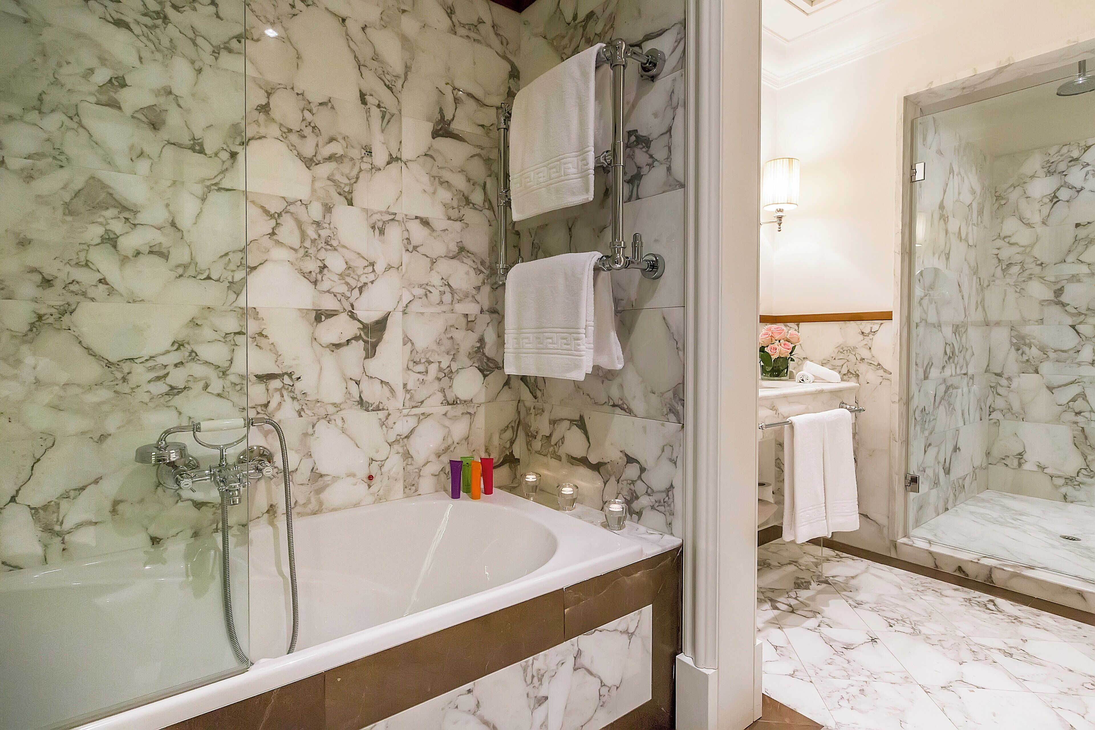 A bathroom with a marble sink, a bathtub, and a glass-enclosed shower.