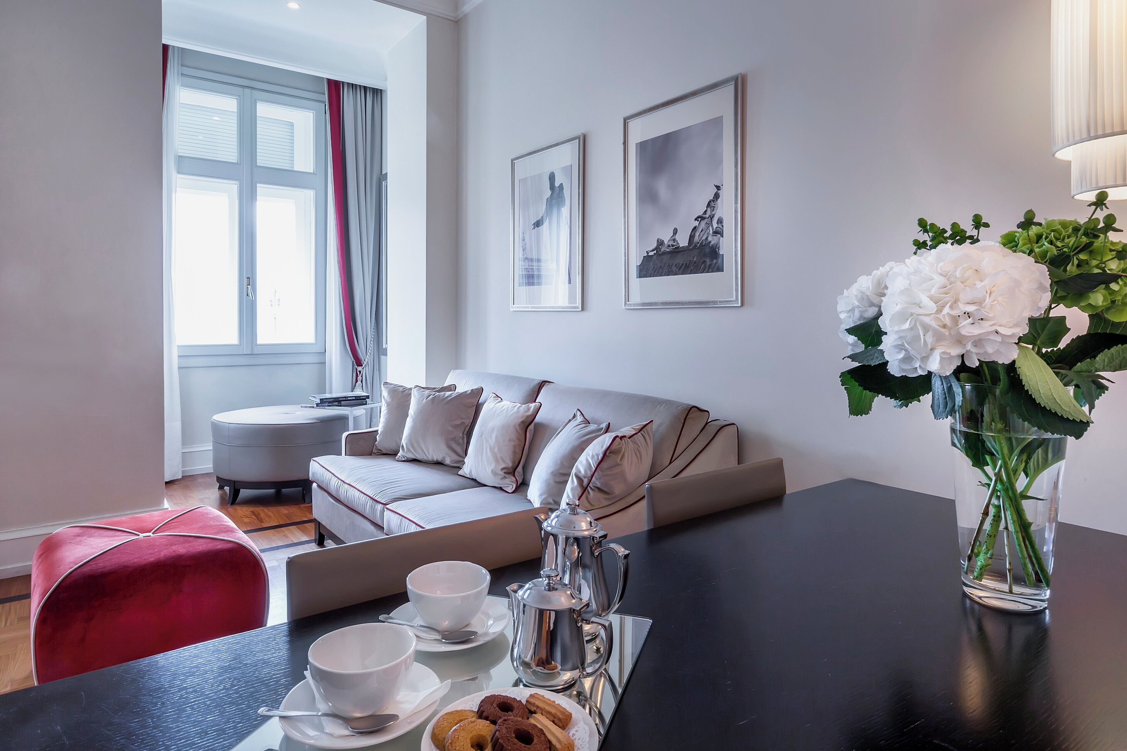 A modern living room with a sofa, a coffee table, and a vase with flowers.