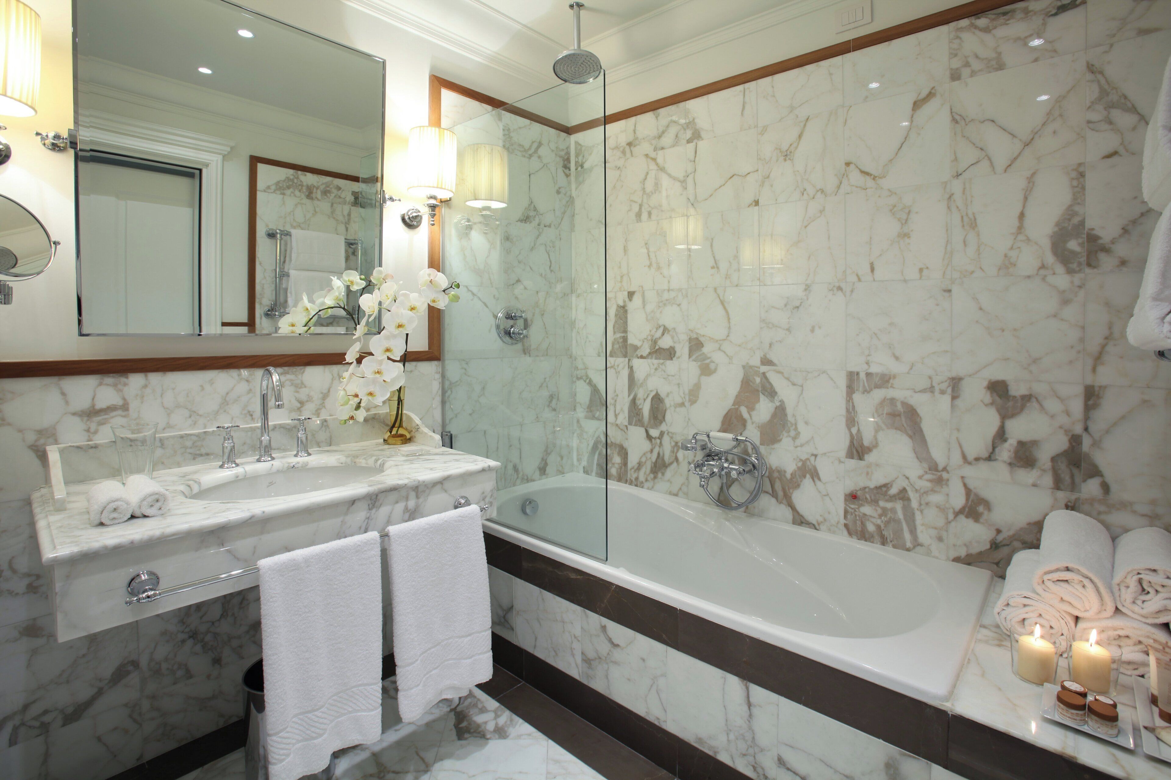 A bathroom with a marble sink, a bathtub, and a glass shower enclosure.