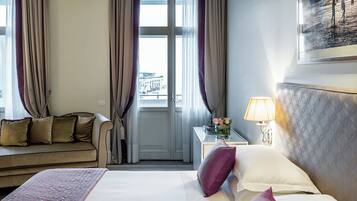 Ein Hotelzimmer mit Bett, Sofa, Nachttisch mit Lampe und einem Fenster mit Vorhängen.