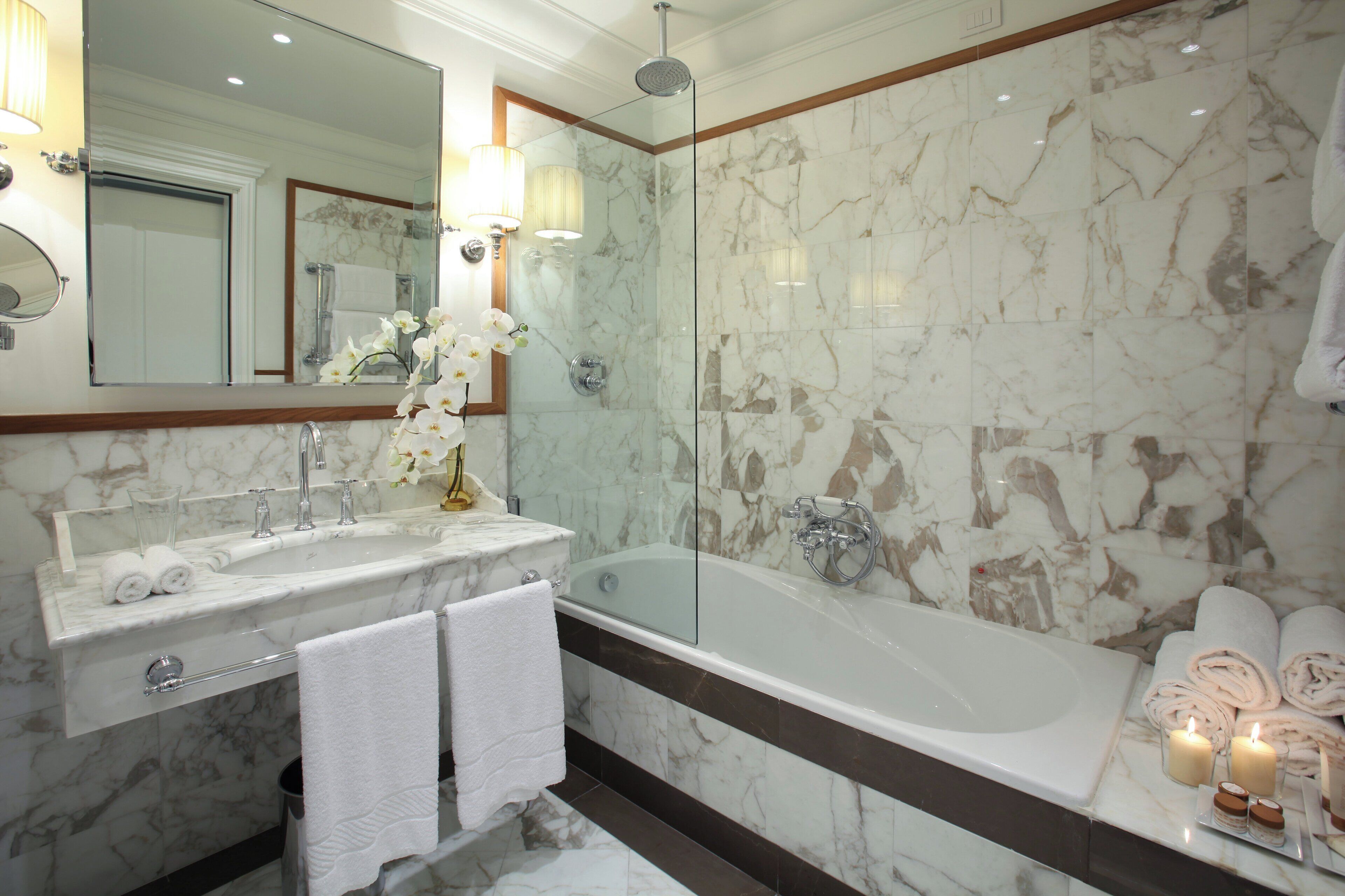 A modern bathroom with a marble sink, a glass-enclosed shower, and a bathtub.