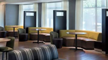 A modern lounge area with sofas, tables, and a patterned bench.