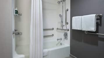 Un baño con bañera, ducha, barras de apoyo y un perchero.