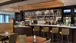 A modern bar area with a counter, stools, and a menu display. - Courtyard by Marriott Norwalk (Norwalk)
