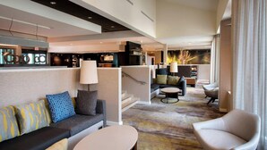 A modern hotel lobby with a sofa, armchairs, a coffee table, and a staircase leading to an upper level. - Courtyard by Marriott Norwalk (Norwalk)