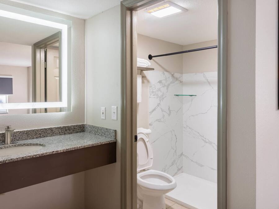 Un baño con pared de mármol, un inodoro y un lavabo con encimera de granito.