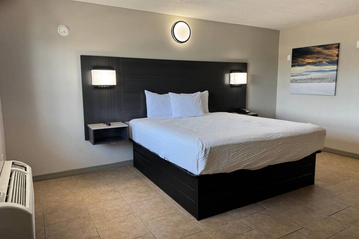 Hotelkamer met een groot bed, twee nachtkastjes, een wandlamp en een schilderij aan de muur.
