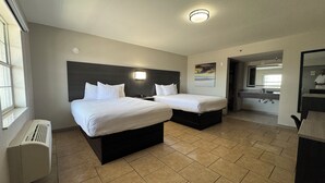 Ein Hotelzimmer mit zwei Betten, einem Badezimmer und einer Küchenzeile.