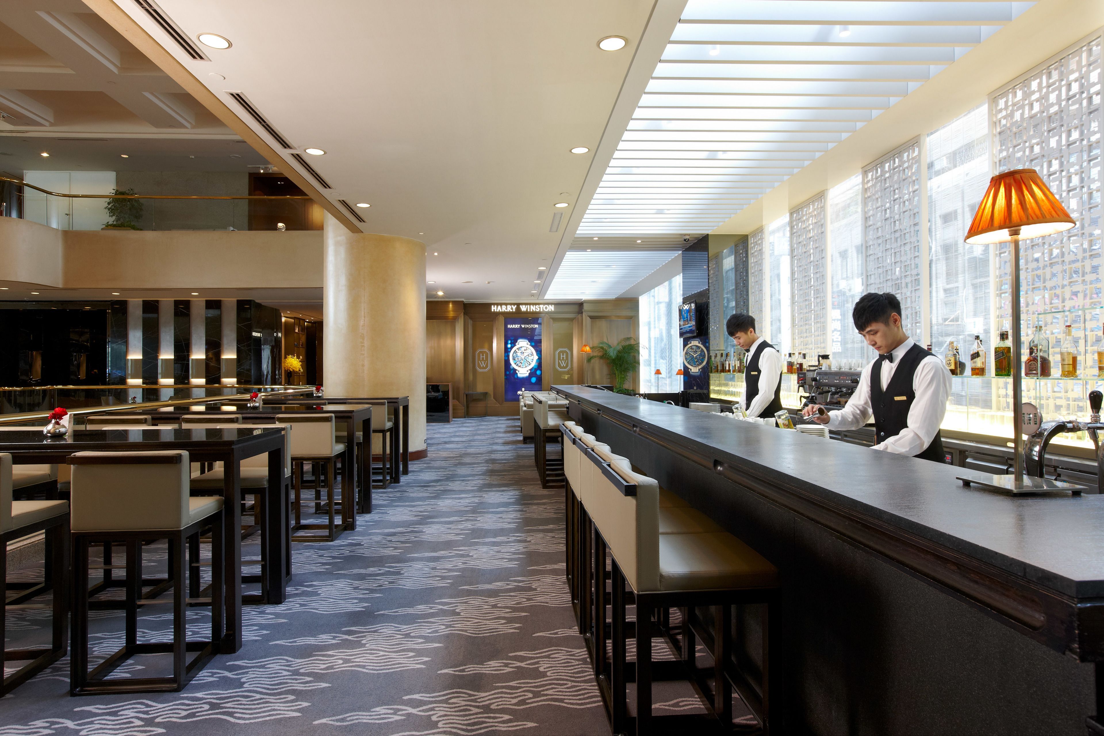 A bar area with a long counter, bar stools, and a patterned carpet.