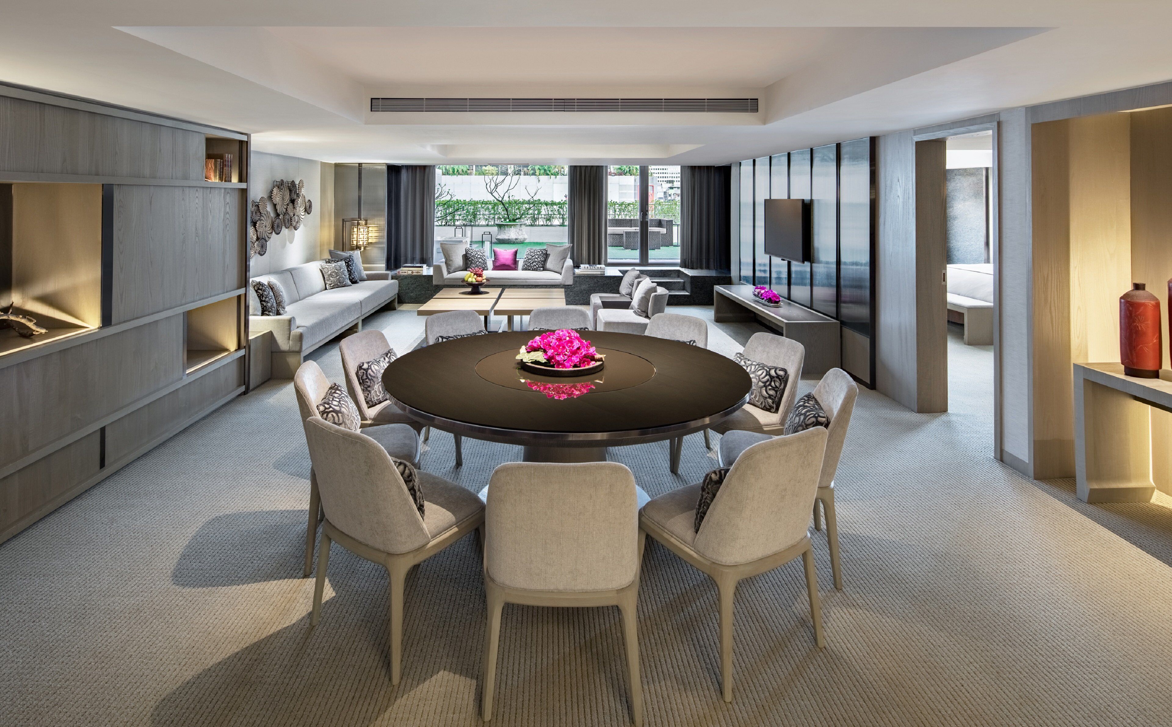 A modern living room with a round dining table, sofas, and a TV.