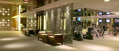 Una hall d'hotel moderna con reception, area lounge e palestra dotata di attrezzature cardio.