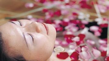A person lying down surrounded by rose petals.