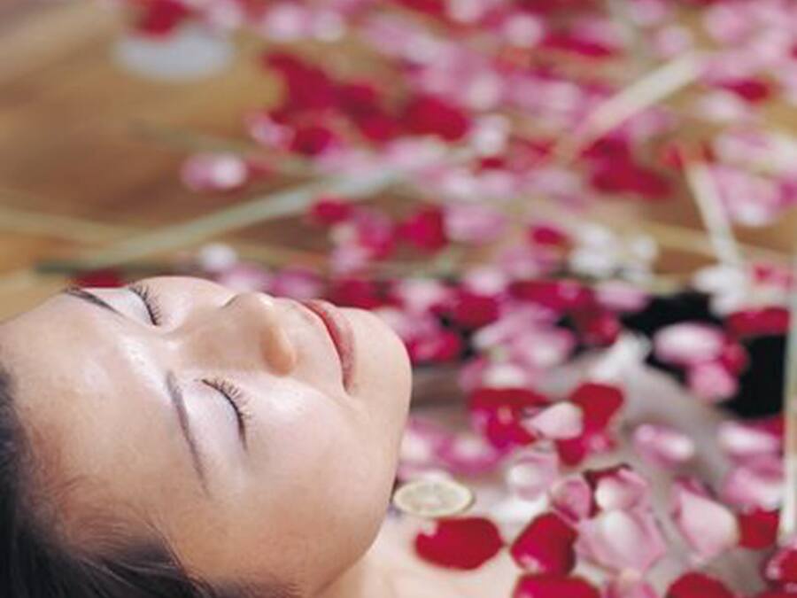 A person lying down surrounded by rose petals.