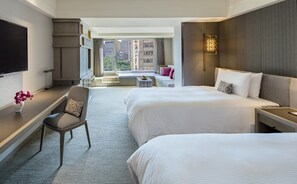 A hotel room with a large bed, a desk, a chair, a TV, and a window with a view of buildings. - Regent Taipei (Taipei)