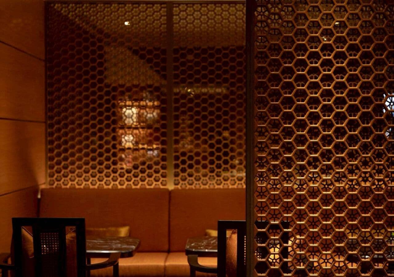 A room with a hexagonal patterned wall, a sofa, and two chairs.