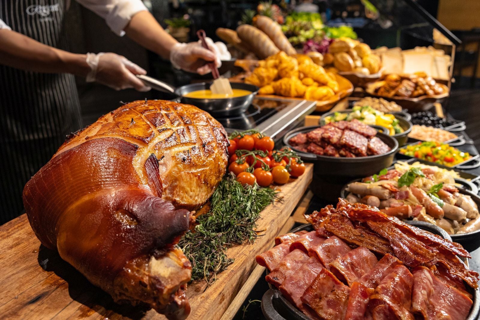 A large roasted ham surrounded by various side dishes and meats.