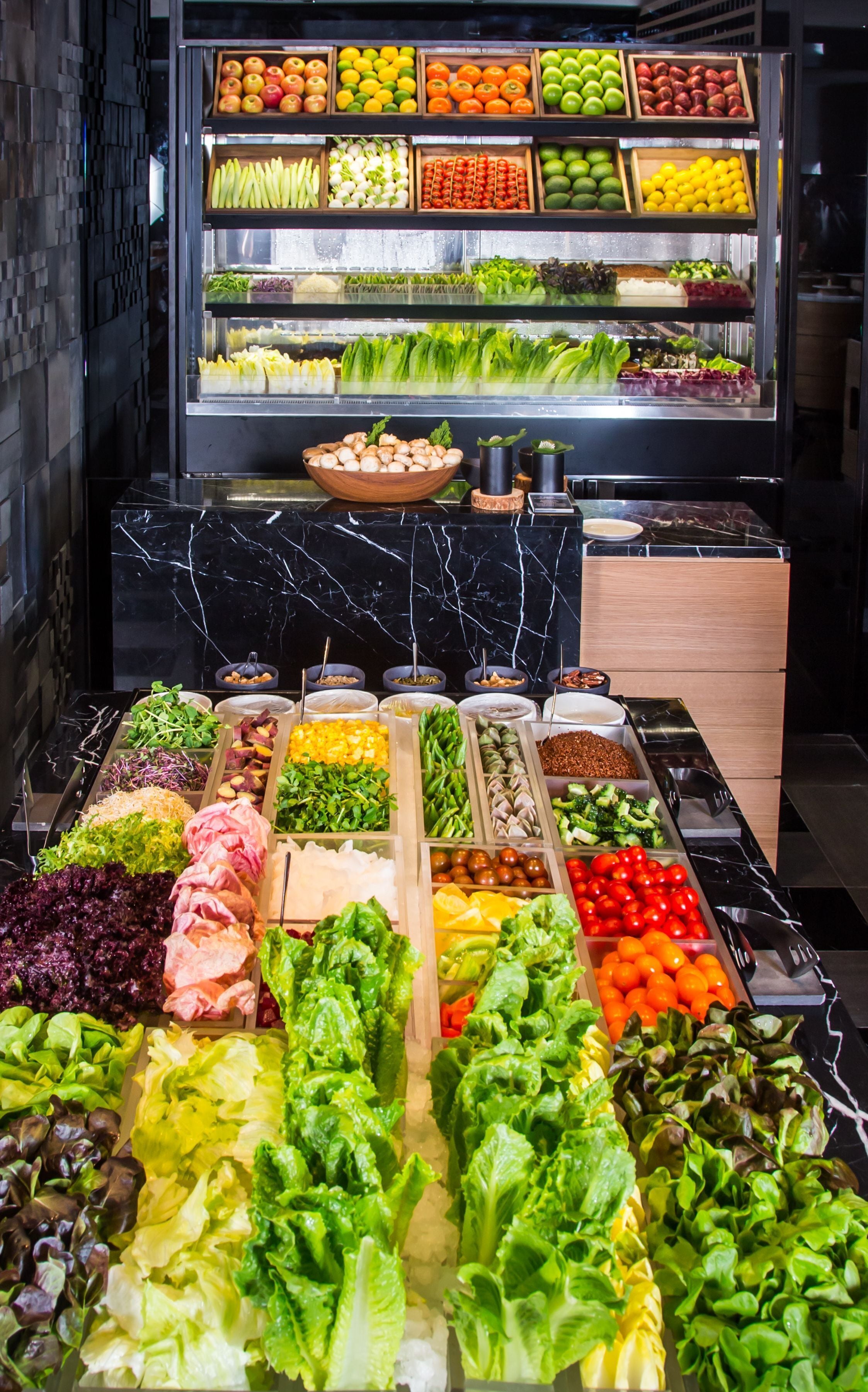 A salad bar with various vegetables and fruits.