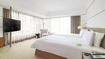 A hotel room with a large bed, a desk with a telephone, a chair, and a television.