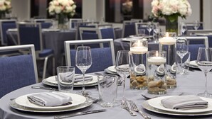 A dining table set with plates, cutlery, glasses, and candles, surrounded by chairs in a formal dining area. - Hilton Houston Plaza/Medical Center (Houston)