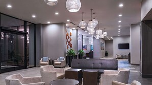 A modern lobby with seating areas, a reception desk, and decorative wall art. - Hilton Houston Plaza/Medical Center (Houston)
