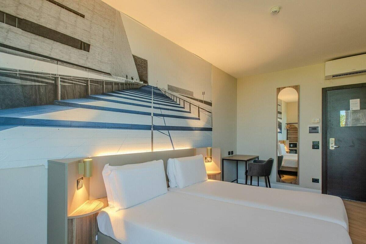 Een moderne hotelkamer met een groot bed, een bureau en een trap naar een hoger niveau.